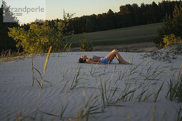 Frau liegt bei Sonnenuntergang im Sand