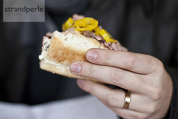 Ein verheirateter Mann hält in einem Feinkostladen in Burien  Washington  ein Sandwich mit italienischem Fleisch und Peperoni in der Hand.