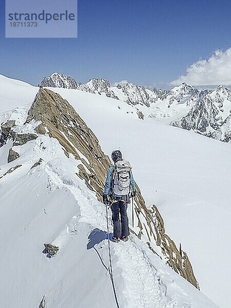 Eine Bergsteigerin auf einem exponierten schneebedeckten Bergrücken in Chamonix