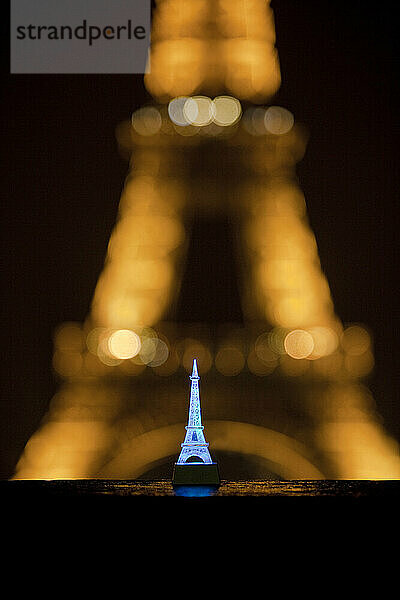 Ein Miniatur-Spielzeug-Eiffelturm vor dem echten Eiffelturm in Paris  Frankreich.