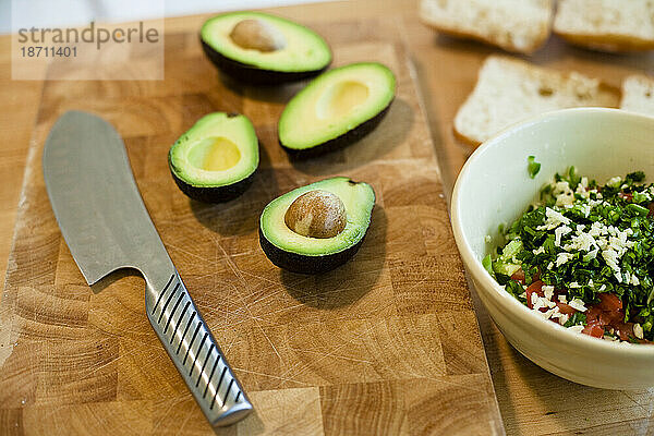 Ein Messer liegt neben Bio-Avocadoscheiben  Brot und einer Schüssel mit Bio-Gemüse in einer Küche in Seattle  Washington.