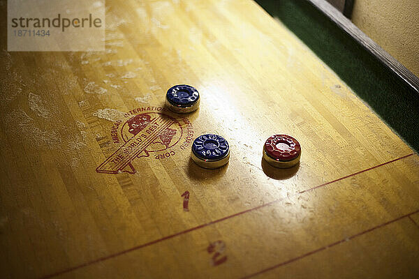 Drei bunte Scheiben liegen auf einem Vintage-Shuffleboard-Tisch aus Holz in einer Bar in Seattle  Washington.