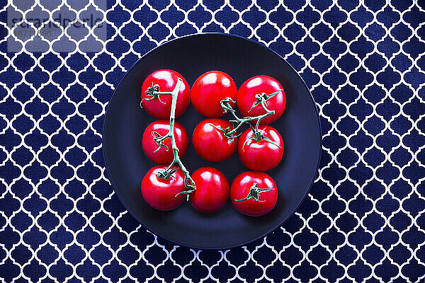 Draufsicht auf frische Tomaten auf schwarzem Teller vor Tischtuch