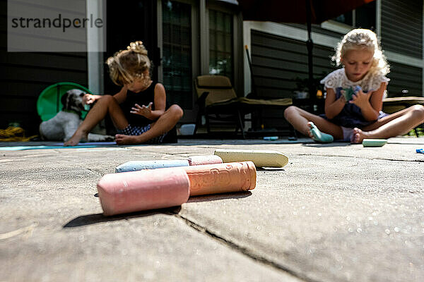 Mädchen zeichnen im Sommer draußen auf der Terrasse mit Kreide
