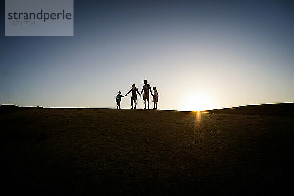 Silhouette einer Familie auf einem Hügel im Sommer