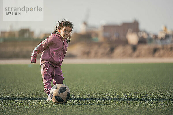 Sportkind. Glückliches kleines Mädchen  das einen Fußball tritt  Kind spielt