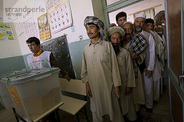 Am Tag der Präsidentschafts- und Provinzwahlen in Mazar-i Sharif  Afghanistan  im August stehen afghanische Männer in der Schlange neben versiegelten Wahlurnen in der Wazir-Akbar-Khan-Schule  um zu wählen