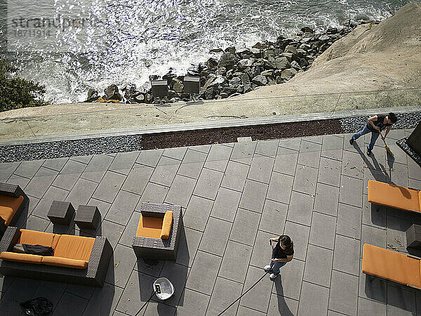 Zwei Putzfrauen fegen und reinigen die Terrasse eines Hauses am Meer in La Jolla  Kalifornien.