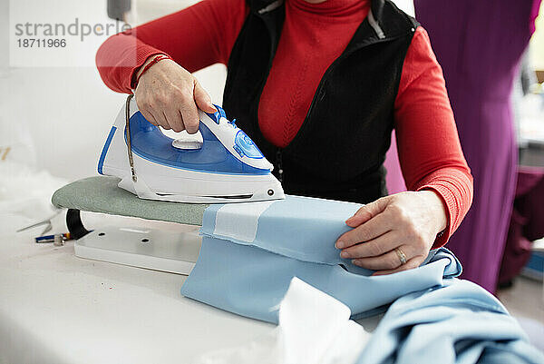 Frau bügelt ein blaues Tuch