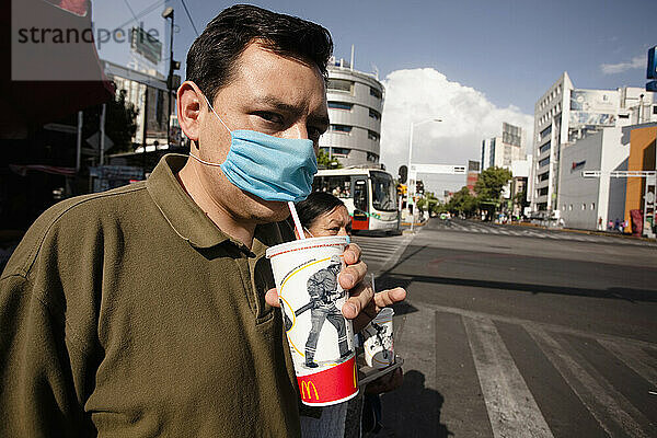 Ein Mann auf der Straße trinkt während der Schweinegrippeepidemie in Mexiko-Stadt durch eine blaue Maske aus einem McDonald's-Becher.
