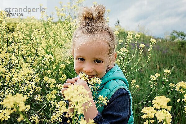 Porträt eines jungen Mädchens  das lächelnd in einem Feld mit gelben Blumen saß