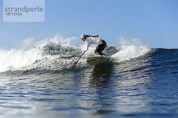 Paddelsurferin reitet auf Welle