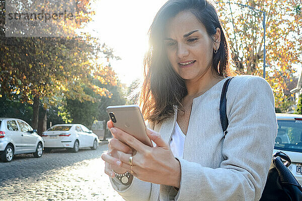 Frau benutzt Smartphone  während sie auf der Straße steht