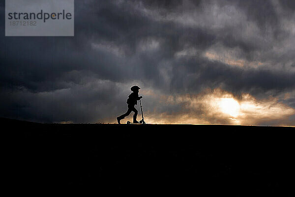 Silhouette eines 5-jährigen Jungen auf einem Roller