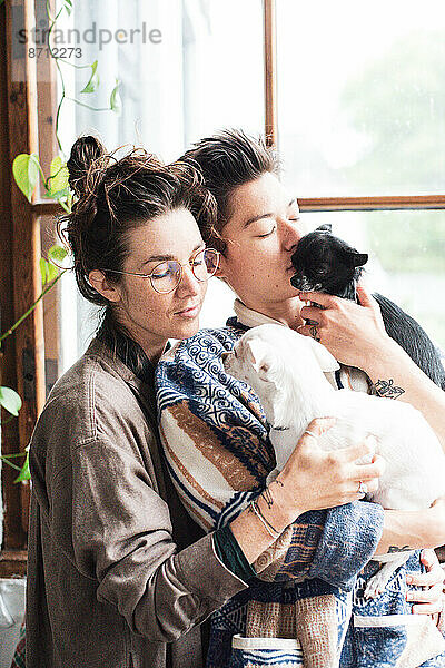 Queeres Paar zu Hause kuschelt sanft mit seinen beiden Chihuahuas