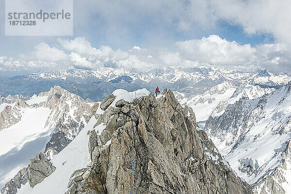 Alpinist posiert hoch oben auf dem berühmten Forbes Arete in den französischen Alpen