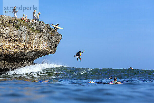 Surfer springen von einer Klippe ins Meer  Jimbaran  Bali  Indonesien