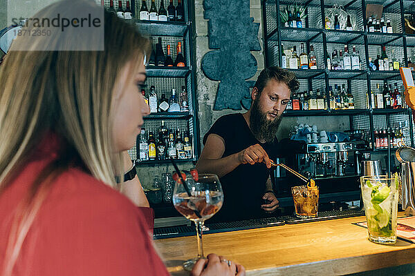 Blondes Mädchen und Barkeeper in einer Cocktailbar.