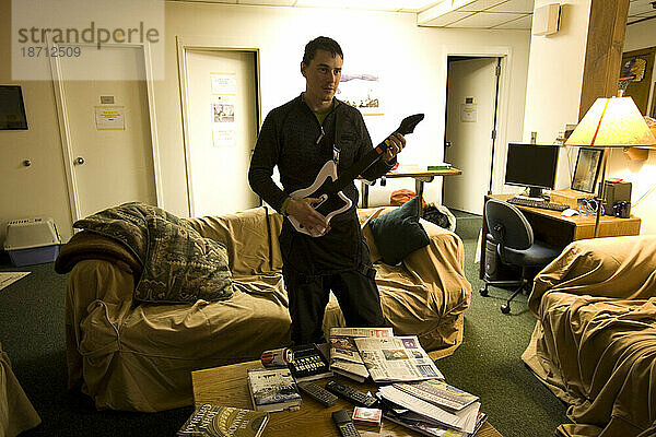 Ein junger Mann entspannt sich im Wohnzimmer des Mt. Washington Observatory und spielt ein Rockmusik-Videospiel.