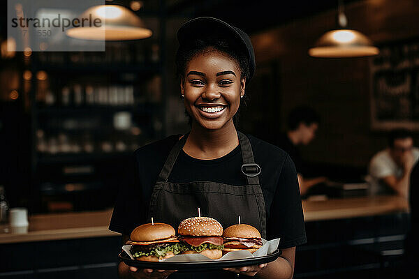 Glückliche afrikanische Kellnerin hält Burger im Restaurant. Generative KI.