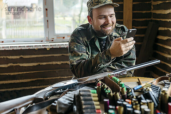 Vorderansicht eines Mannes  der eine Pause macht  während er seine Schrotflinte für den Telefongebrauch vorbereitet  Tichwin  Sankt Petersburg  Russland