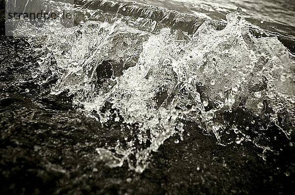 Eine kleine Welle bricht am Strand eines Sees zusammen.