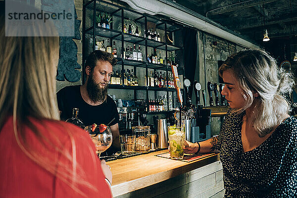 Zwei Freundinnen und Barmann in einer Cocktailbar.