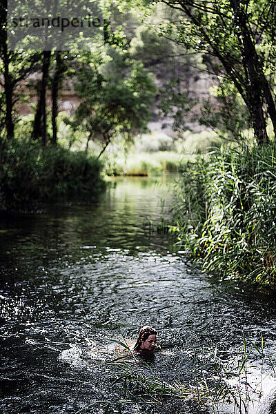 Blonde Frau badet im wunderschönen Flusswasserfall.