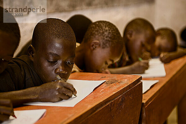 Jungen arbeiten an ihren Schreibtischen in einem ruandischen Schulhaus.