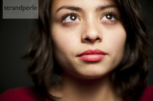 Low-Angle-Studioporträt eines 15-jährigen Latina-Mädchens  das nach oben schaut.