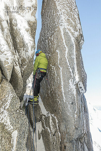 Alpinist navigiert durch einen Schornstein zwischen zwei schmutzverkrusteten Türmen des Mt. Blanc