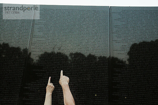 Menschen berühren und zeigen auf Namen auf der Vietnam Veterans Memorial Wall in Washington  D.C.