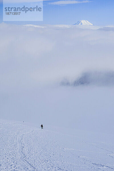 Ein einsamer Bergsteiger nähert sich dem Camp Muir des Mount Rainier  dahinter Mt. Adams