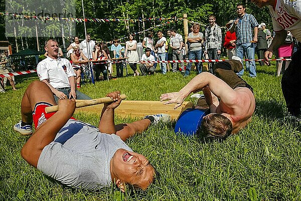 Männer führen Mas-Wrestling-Spiel im Stadtpark mit traditionellem Stock durch