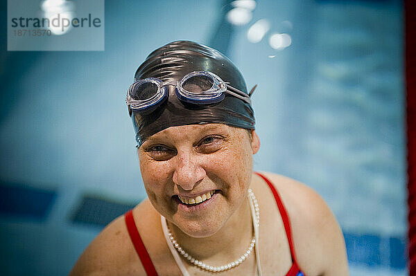 Eine querschnittsgelähmte Sportlerin lächelt  bevor sie mit dem Schwimmtraining beginnt.