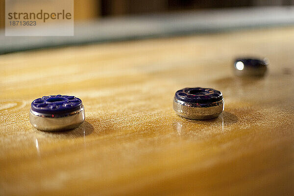 Drei bunte Scheiben liegen auf einem Vintage-Shuffleboard-Tisch aus Holz in einer Bar in Seattle  Washington.