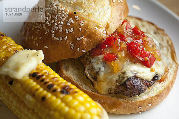 Ein frisch gegrillter Hamburger mit hausgemachtem Relish liegt auf einem Teller neben einem Maiskolben aus gegrilltem Bio-Mais mit Butter in Seattle  Washington.