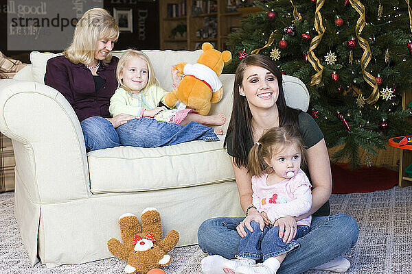 Zwei Frauen entspannen sich mit ihren Kindern  nachdem sie ihren Weihnachtsbaum aufgestellt haben.
