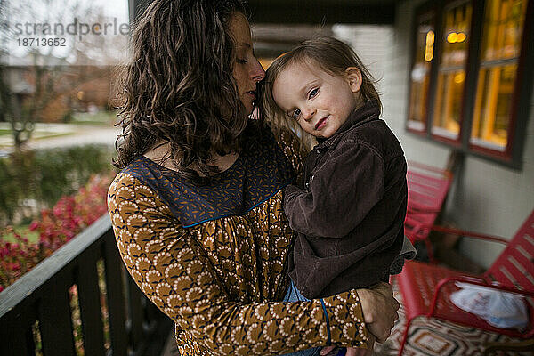 Eine liebevolle Mutter hält ihr kleines Kind auf der Veranda fest in den Armen