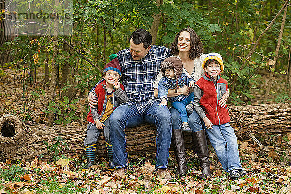 Porträt einer Familie  die zusammen in einem bewaldeten Park sitzt