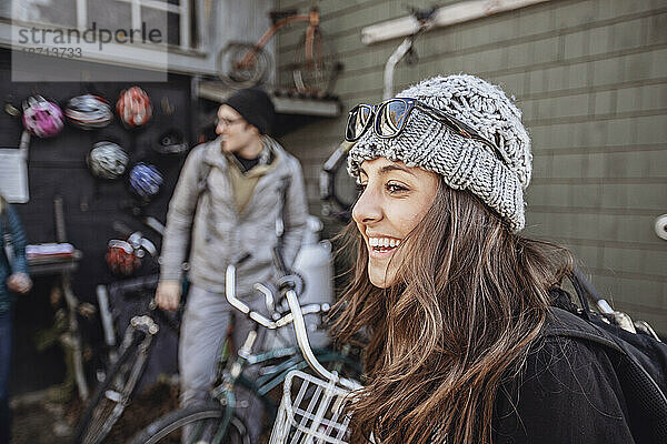 Eine junge Frau lächelt  während sie sich Fahrräder zum Mieten in Maine ansieht