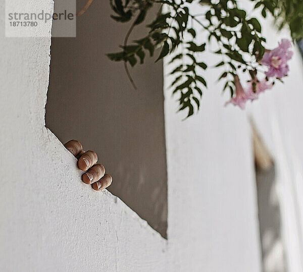 Eine Hand hält sich an einem Fensterbrett eines Stuckgebäudes in Marrakesch fest