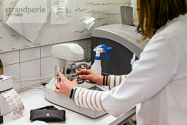 Optiker schneidet Brillenglas in einer Optikerwerkstatt