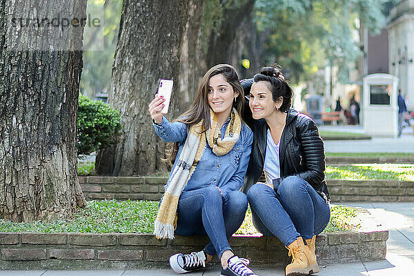 Frauen sitzen auf der Straße und machen ein Selfie