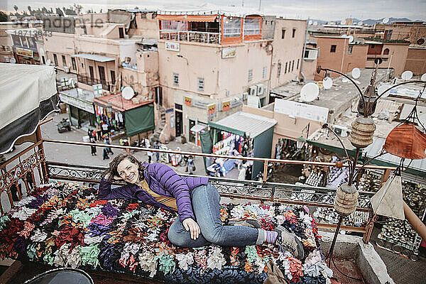 Eine lächelnde Frau entspannt sich auf einem Dach mit Blick auf Marrakesch  Marokko