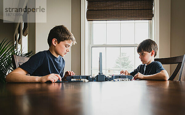 Zwei Jungen spielen gemeinsam ein Brettspiel an einem Holztisch.