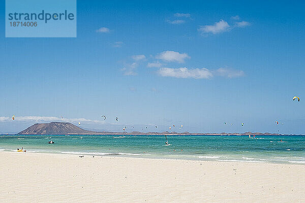 Landschaft eines paradiesischen Strandes mit gelbem Sand und Kitesurfern
