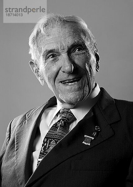 Ein Veteran des Zweiten Weltkriegs lächelt und blickt nach einem Porträt über seine Schulter.