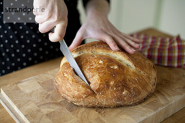 Eine junge Frau schneidet in ihrem Haus in Seattle  Washington  ein frisches  selbstgebackenes Bio-Brot.