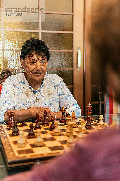 Zwei moderne ältere Frauen spielen zu Hause Schach